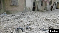 A man walks next to rubble on a street with damaged houses in Baba Amro, near Homs, on February 8.