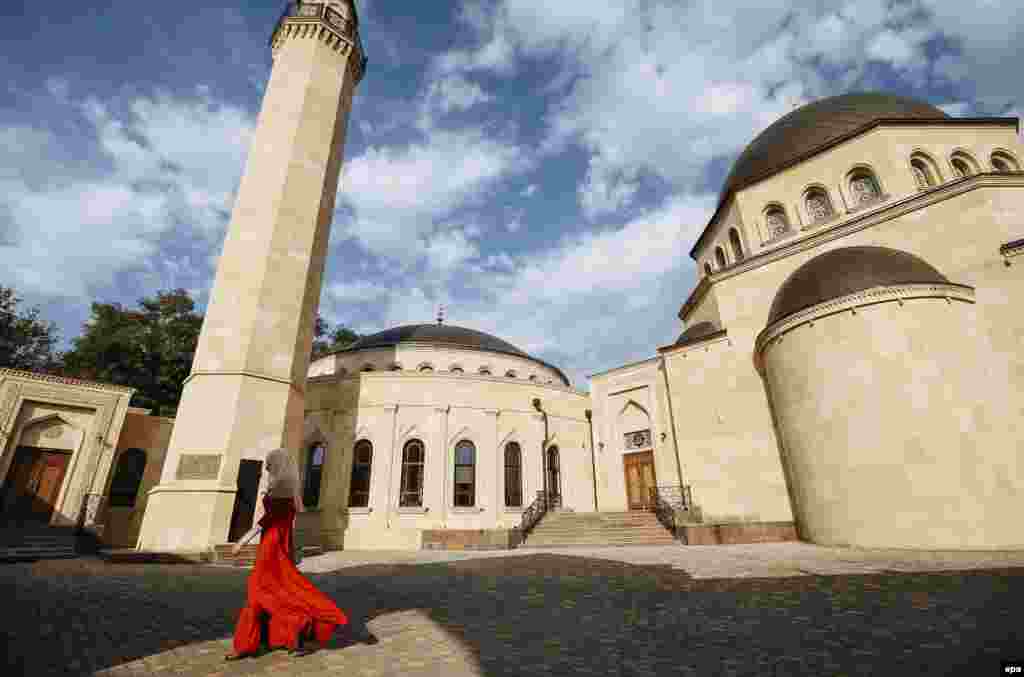 A Ukrainian woman walks next to the Ar-Rahma Mosque during celebrations marking Eid al-Adha in Kyiv. The festival is celebrated by slaughtering goats, sheep, and cattle in commemoration of the Prophet Abraham's readiness to sacrifice his son to show obedience to God. (epa/Roman Pilipey)