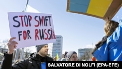 Демонстранты требуют отключить Россию от SWIFT во время акции протеста против российского вторжения в Украину. Женева, 26 февраля 2022 года