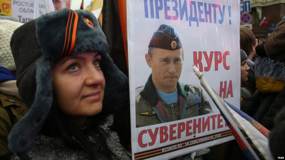 A woman holds a placard depicting Russian President Vladimir Putin as she takes part in a march marking Russia's National Unity Day on Tverskaya Street in Moscow on November 4.