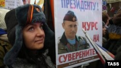 A woman holds a placard depicting Russian President Vladimir Putin as she takes part in a march marking Russia's National Unity Day on Tverskaya Street in Moscow on November 4.