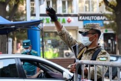 An officer raises his hand as a traffic policeman checks the ID of a driver at a checkpoint amid the ongoing coronavirus disease pandemic in Tashkent on July 23.