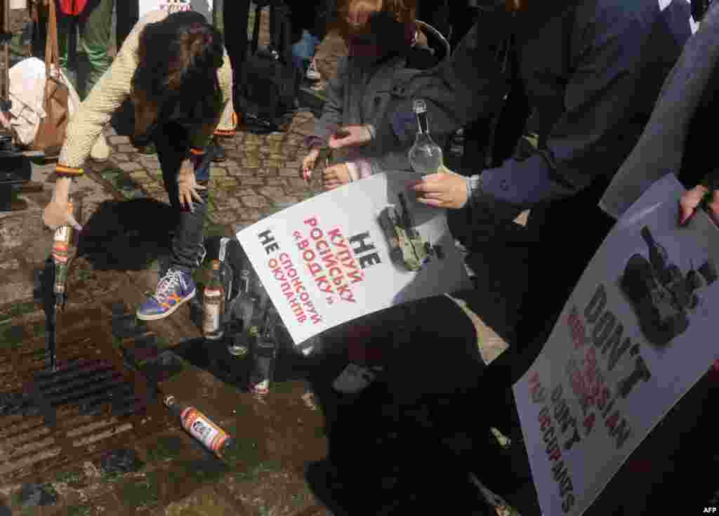 People hold signs reading &quot; Don&#39;t buy Russian vodka. Don&#39;t pay occupiers&quot; as they empty bottles of vodka into the sewer during a flash mob in the center of the western city of Lviv, Ukraine. (AFP/Yuriy Dyachyshyn)