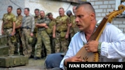 Украинец играет на бандуре на похоронах украинских солдат, воевавших с пророссийскими боевиками.