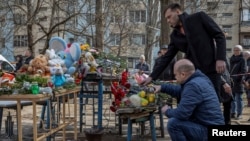 Люди кладуть квіти та іграшки біля імпровізованого меморіалу жертвам удару безпілотника по будинку в Одесі, 3 березня 2024 року