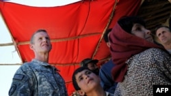 Young Afghan children look on as U.S. General Stanley McChrystal (left) visits a local bazaar at the Baraki Barak district in Logar Province earlier this month.