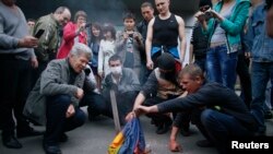 Protestatari pro-ruși ard un drapel ucrainean in Donețk, pe 4 mai, 2014