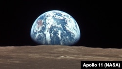 Жердин Айдан чыгышы, Жымжырт деңизи ай көлү (лунное море). Сүрөттү Аполло–11 кемесиндеги астронавт Майкл Коллинз тарткан, 16-июль 1969-ж.