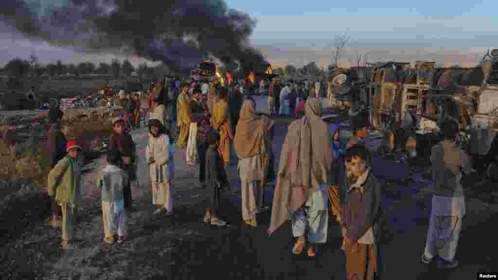 Residents stand near fuel trucks set ablaze in the Bolan district of Balochistan Province in Pakistan in December.