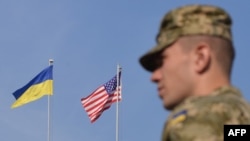 A Ukrainian serviceman stands in front of U.S. and Ukrainian flags during the opening ceremony of the Rapid Trident military exercises near the western Ukrainian town of Yavoriv on September 15.