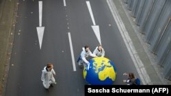 Илустрација - Демонстранти вртат огромен глобус низ улица додека учествуваат во таканаречен климатски марш. 
