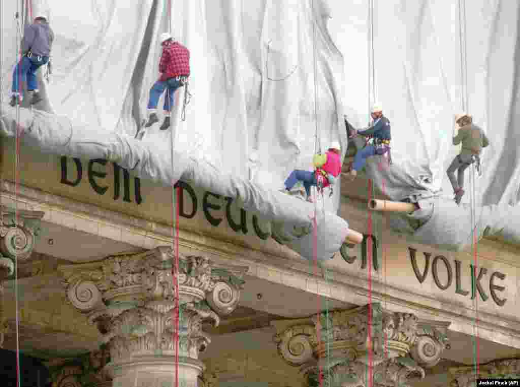 Climbers lower silver fabric from the main portal of the Reichstag in Berlin on June 19, 1995. &quot;It was one of the most beautiful things I have ever seen: 100 rock climbers abseiling down the facade of the Reichstag, slowly unfurling this huge silvery curtain,&quot; Christo told The Guardian in 2017. &quot;There were no cranes or machinery, just people descending in a kind of aerial ballet.&quot;