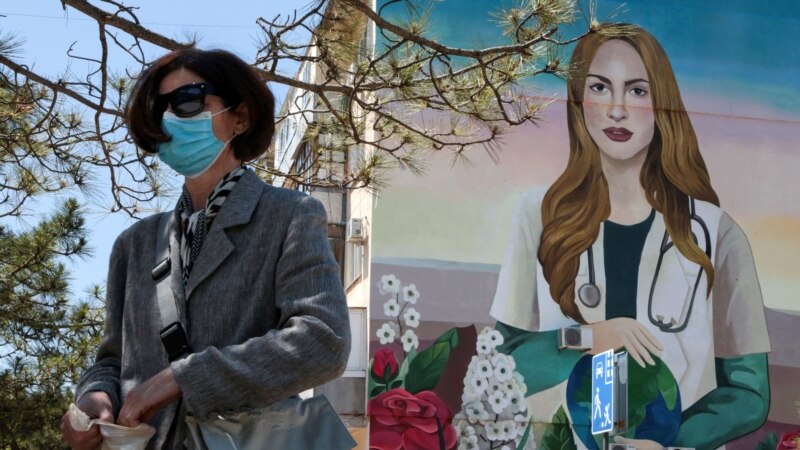 Женщина в «защите» от коронавируса на фоне рисунка, посвященного медикам | Крымское фото дня