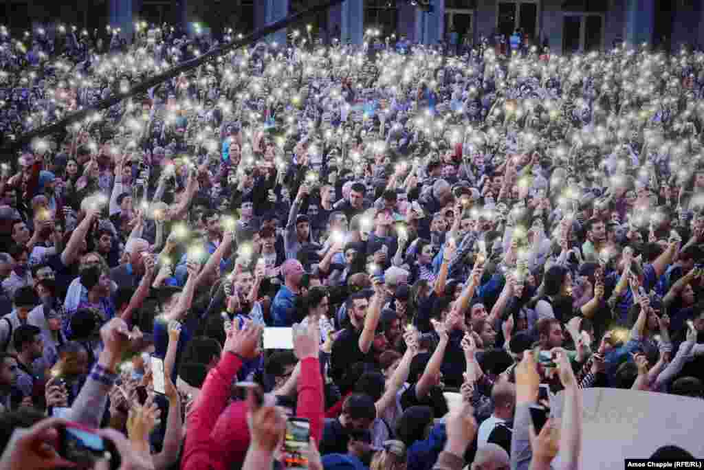 Antigovernment protesters in Tbilisi hold their cell phones aloft as protest leader Zaza Saralidze speaks to the crowd on June 1 in the Georgian capital. The mass rallies began on May 31 as a protest against the verdict in the trial of two young men suspected of murdering a teenager. (RFE/RL/Amos Chapple)
