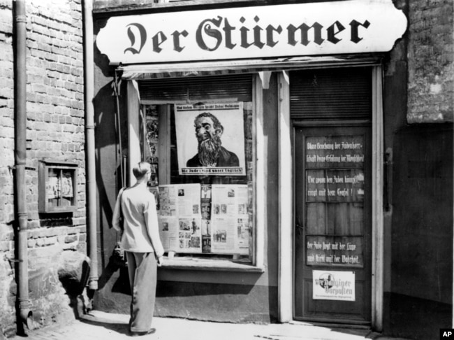Un homme regarde une caricature antisémite affichée dans la vitrine du journal anti-juif Der Stuermer lors de l'invasion nazie de la ville libre de Danzig, en Pologne, le 10 juillet 1939.