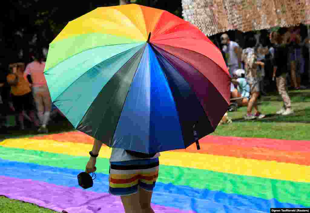 O persoană merge cu o umbrelă colorată în culorile curcubeului, în timp ce oamenii participă la cea de-a doua paradă a Gay Pride din Skopje, Macedonia de Nord, 26 iunie 2021.