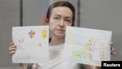 RFE/RL journalist Alsu Kurmasheva attends a court hearing in Kazan, Russia, on May 31, where she showed reporters children's drawings she has received from supporters.