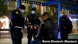 Szlovén rendőrök igazoltatnak egy férfit 2020. október 20-án. Szlovéniában a járvány miatt kijárási tilalom lépett életbe 21 óra után.