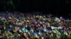 Местные жители стоят среди флагов во время церемонии похорон украинских военнослужащих, иллюстративное фото 