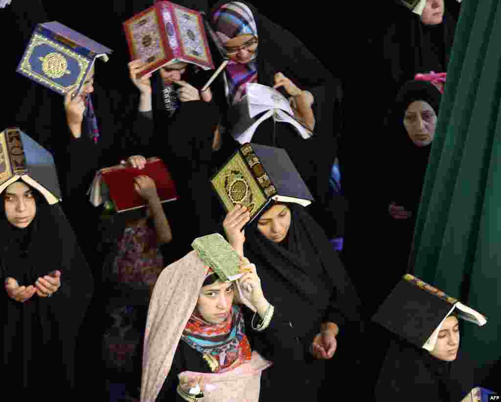 Shi&#39;ite Muslim worshipers place the Koran over their heads as they attend a Lailat al-Qadr (Night of Destiny) prayer in the Imam Musa al-Khadim shrine in Baghdad. (AFP/Ahmad al-Rubaye)