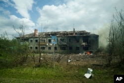 A damaged building in Vovchansk smolders after the village was hit by a Russian air strike earlier this month.