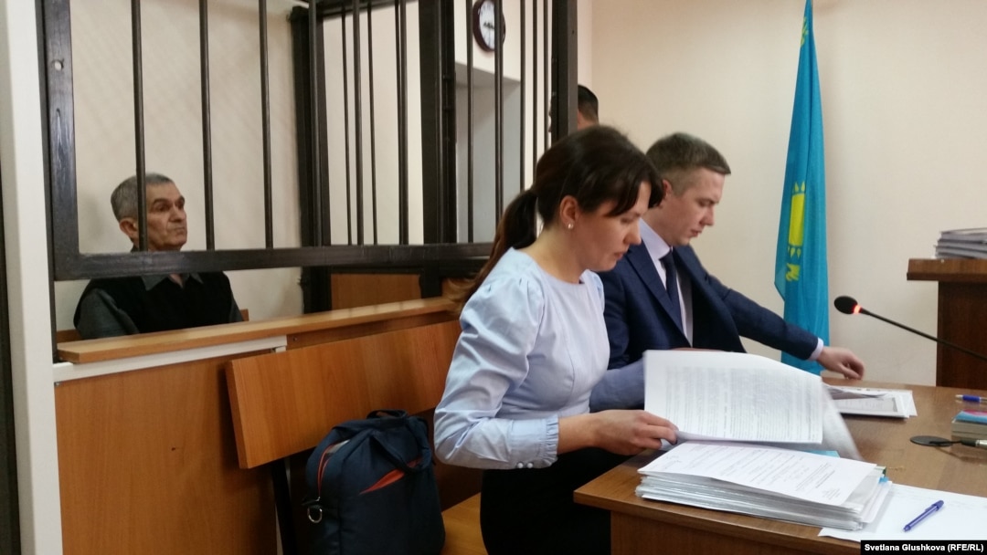 Teimur Akhmedov (left), in the defendant's cage, and his lawyers in an Astana courtroom on March 27.