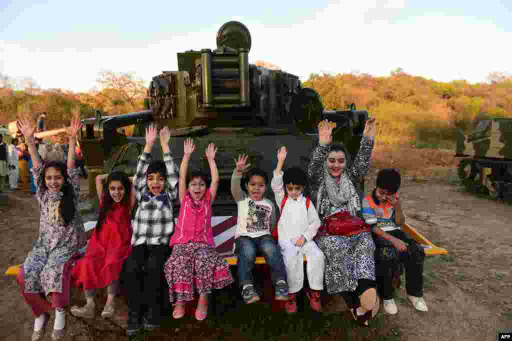 Pakistani children sit on a tank as they enjoy a public holiday ahead of the National Day celebration in Rawalpindi. (AFP/Farooq Naeem)