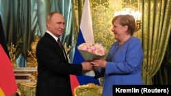 Vladimir Putin îi oferă flori Angelei Merkel în timpul întâlnirii de la Kremlin, 20 august 2021