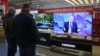 Посетители магазина бытовой техники в Крыму смотрят трансляцию пресс-конференции президента России Владимира Путина, 17 декабря 2020 года