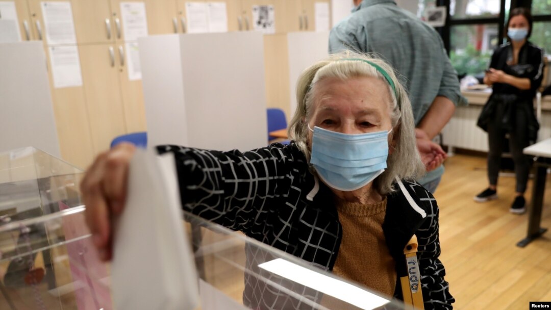 O alegătoare purtând mască votează în cadrul alegerilor naționale, la o secție de votare din Belgrad.