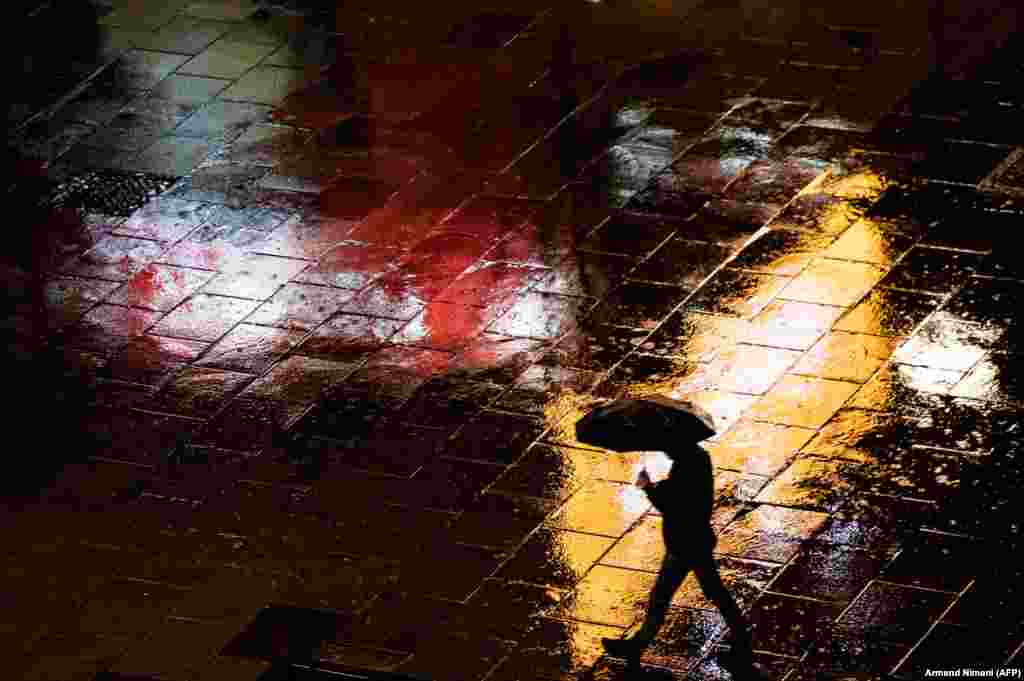 A pedestrian walks under an umbrella during a rain shower on Mother Teresa Square in Pristina, Kosovo. (AFP/Armend Nimani)