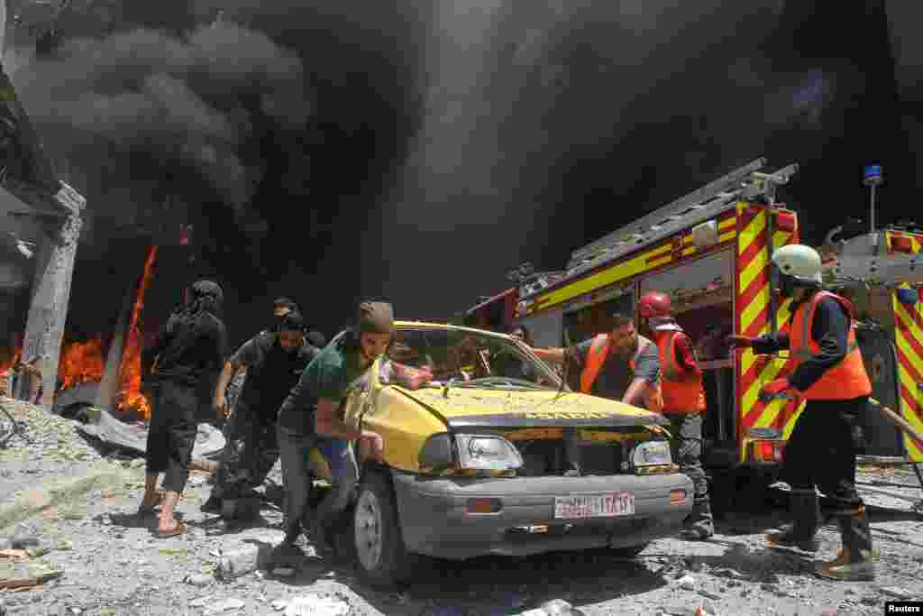 Civil-defense members and rescuers push a car at a site hit by air strikes in Idlib, Syria. (Reuters/Ammar Abdullah)