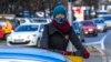 MACEDONIA -- A woman wears a protective mask while riding her bicycle between cars in the center of Skopje, December 27, 2017