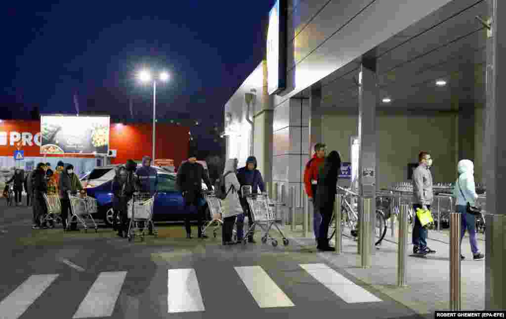 People queue at the entrance of a supermarket while keeping a safe distance from one another in Bucharest, Romania. Romanian President Klaus Iohannis announced a lockdown across the country on March 25 and asked the army to help enforce the new measures.&nbsp;