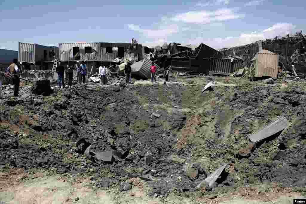 People stand at the site of a massive crater following a suicide car-bomb attack at a compound in Kabul that is used by foreign firms supplying equipment to NATO. Four police officers and two civilians were killed, as well as the four attackers. The Taliban claimed responsibility. (Reuters/Mohammad Ismail)