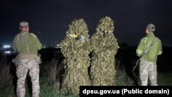 Fotografie publicată de grănicerii ucraineni cu doi bărbați reținuți în regiunea Odesa, în timp ce încercau să treacă ilegal frontiera ucraineano-moldoveană pe segmentul transnistrean, deghizați în costume de camuflaj.