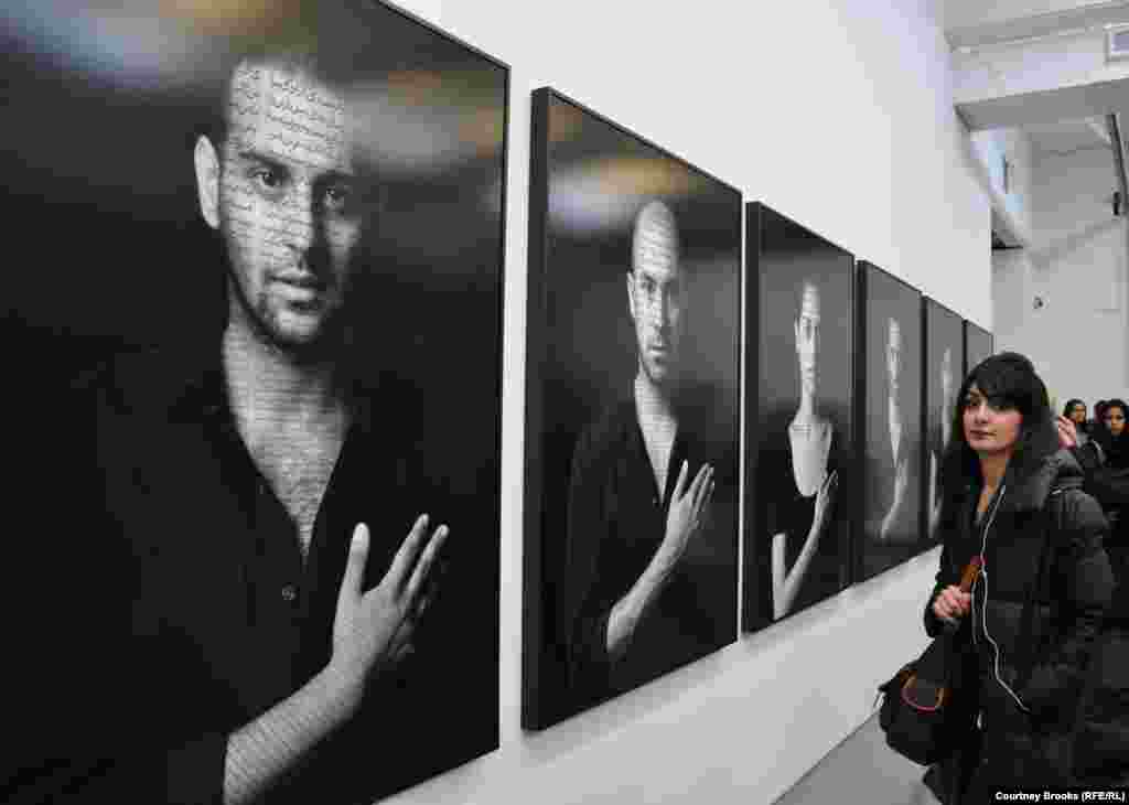 A woman looks at photos of "The Patriots," representations of those who fight against those who hold power.