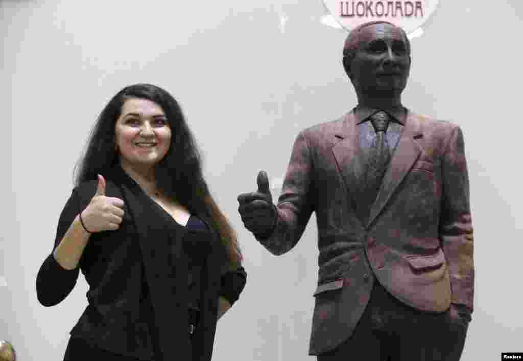 A visitor poses for a picture near a life-sized statue of Russian President Vladimir Putin made out of chocolate that is on display at the Festival of Chocolate fair in St. Petersburg. (Reuters/Peter Kovalev)