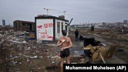 A 14-year-old Afghan migrant showers on a cold day near an old train carriage where he took refuge in Belgrade