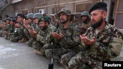 Afghan National Army soldiers pray for their fallen colleagues.