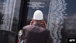 Një burrë shikon pllakën përkujtimore ku janë shkruar emrat e personave të vrarë gjatë luftës më 199 në fshatin Rrezallë. Fotografi nga arkivi.
