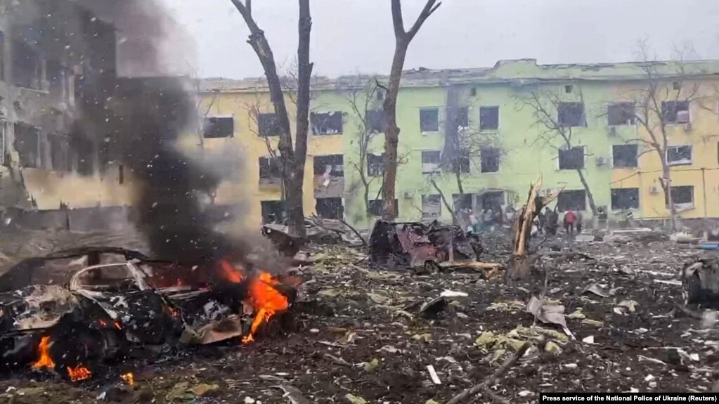 Disa automjete dhe një ndërtesë spitali shihen të shkatërruara nga sulmi ajror rus, në Mariupol, më 9 mars.