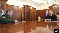 Russian President Vladimir Putin (right) speaks with the chief of Russia's General Staff, General Valery Gerasimov, during a meeting at the Kremlin on April 19.
