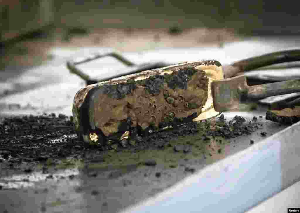 A newly solid gold alloy bar comes out of the mold. 