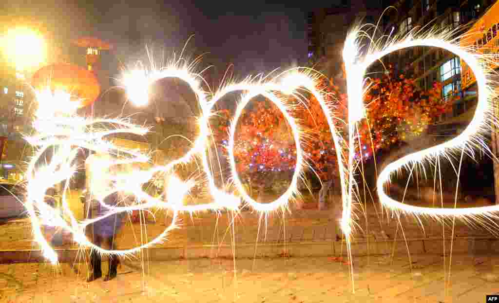 A reveler writes "Dragon" in traditional Chinese characters and 2012 with fireworks in Beijing.