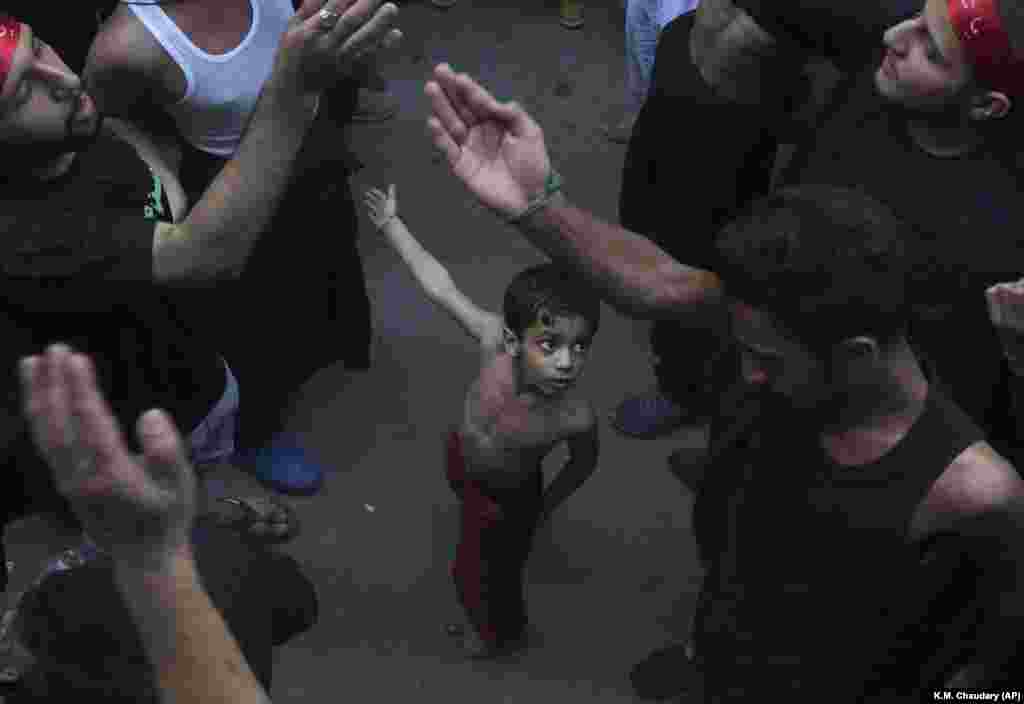 A Shi&#39;ite Muslim child in the Pakistani city of Lahore beats his chest next to his father during a procession to mark the end of the 40-day mourning period following the anniversary of the 7th-century death of Imam Hussein, the Prophet Muhammad&#39;s grandson. (AP/K.M. Chaudary)