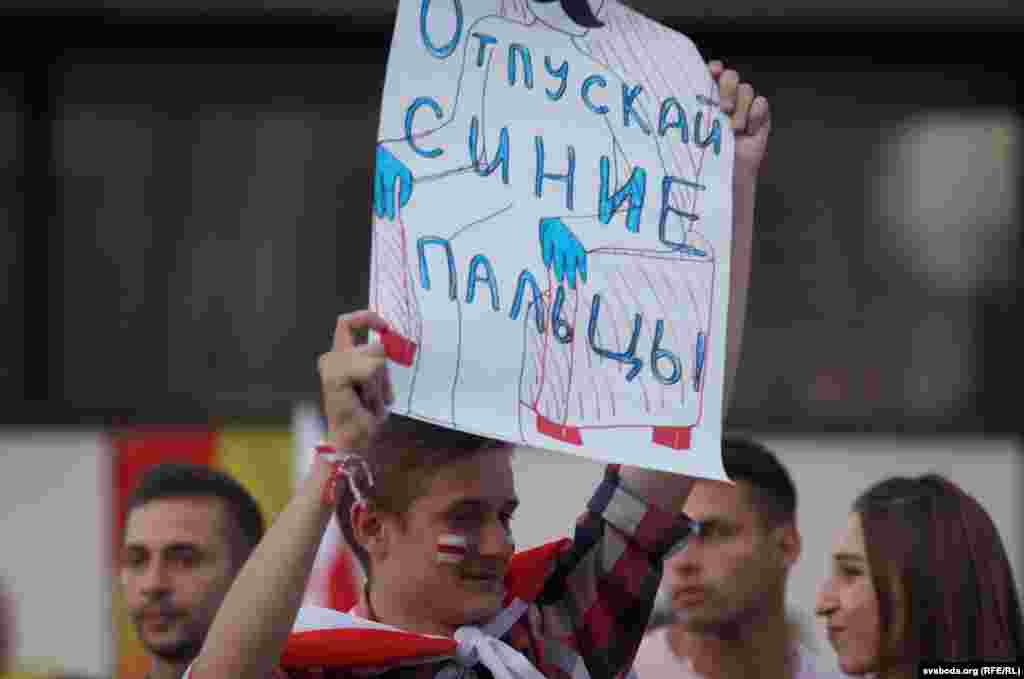 The sign says: &quot;Let go with the blue fingers.&quot; It&#39;s a reference to a statement in November 2019 by Lukashenka. He told reporters then that he would not hold on to the presidency with fingers that would turn blue from gripping it too tightly.