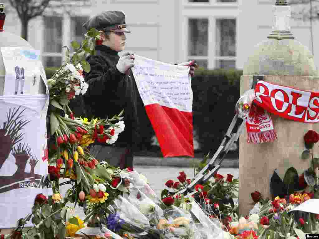 A scout holds a Polish national flag in front of the presidential palace.