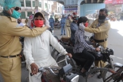 Volunteers distribute protective face masks to people on a road during a partial lockdown in the Punjabi city of Multan.