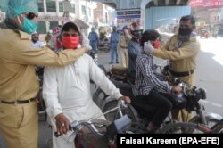 Volunteers distribute protective face masks to people on a road during a partial lockdown in the Punjabi city of Multan.
